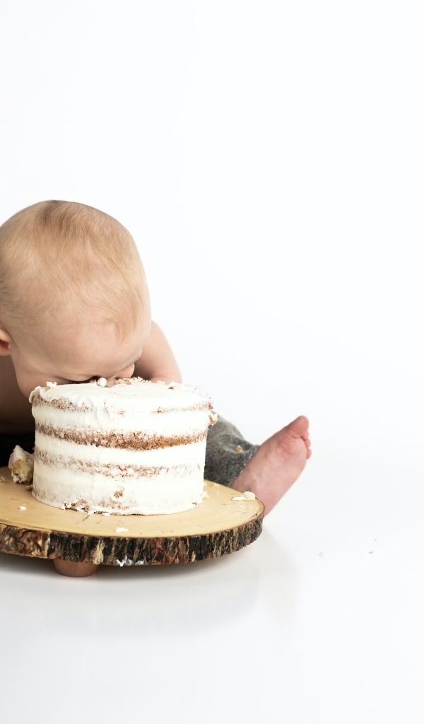 Маленький мальчик ест праздничный торт на белом фоне