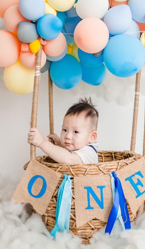 Маленький мальчик в корзине с воздушными шарами