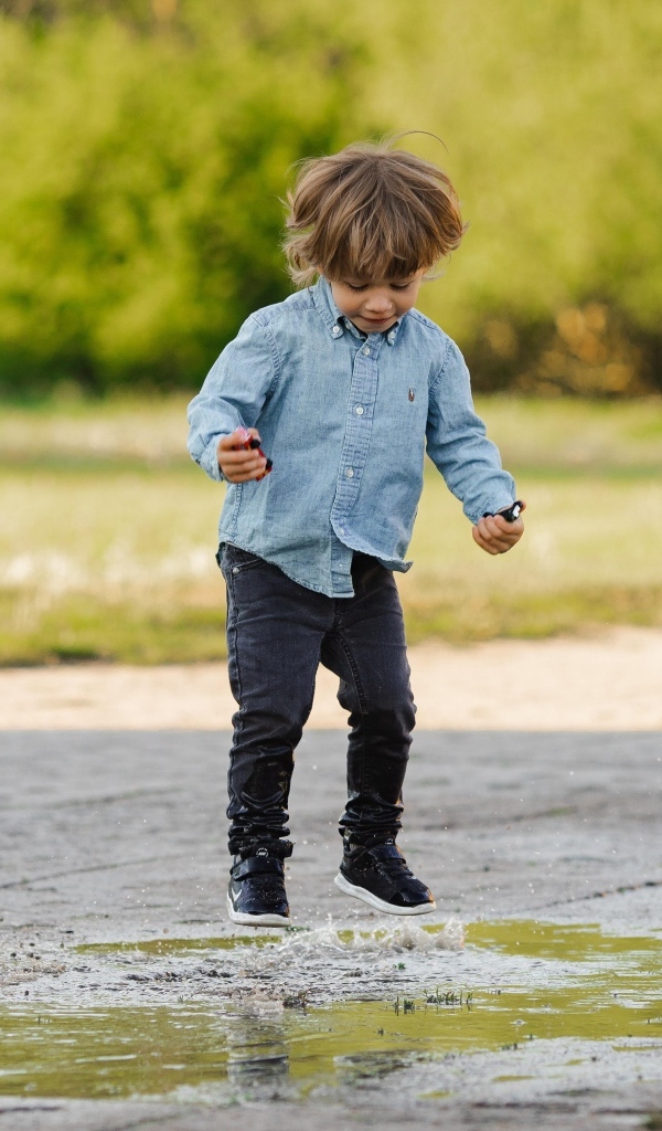 Маленький  мальчик прыгает по лужам