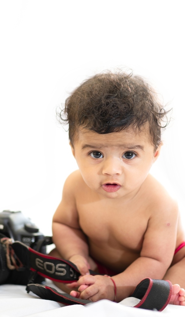 Маленький мальчик с фотоаппаратом на белом фоне