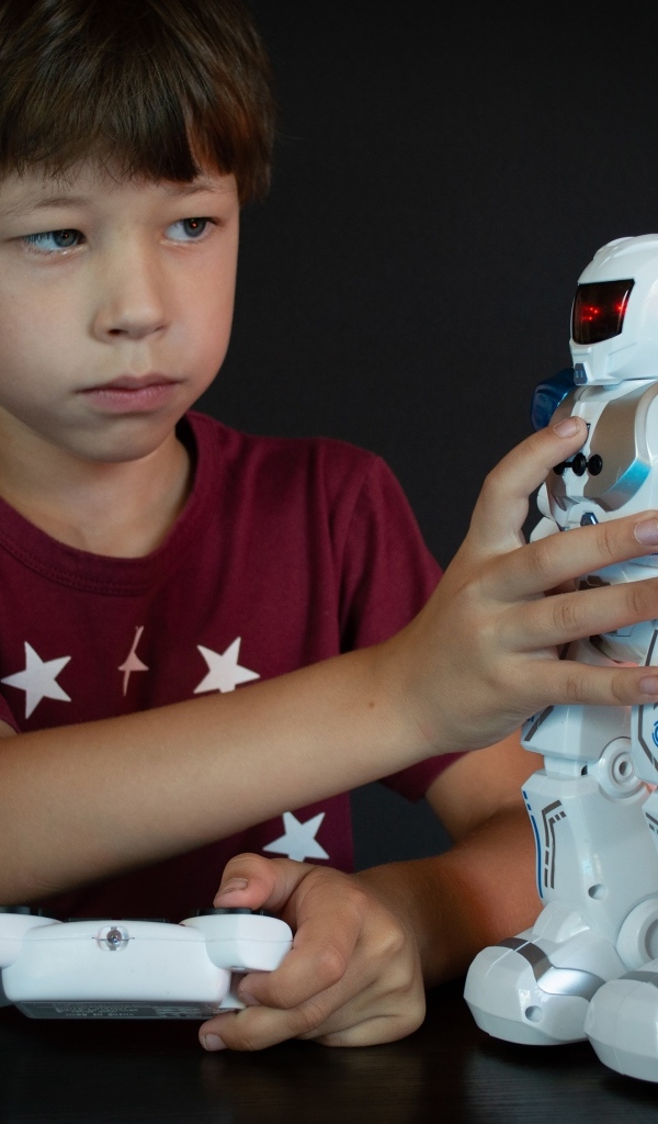 Маленький мальчик с роботом на черном фоне