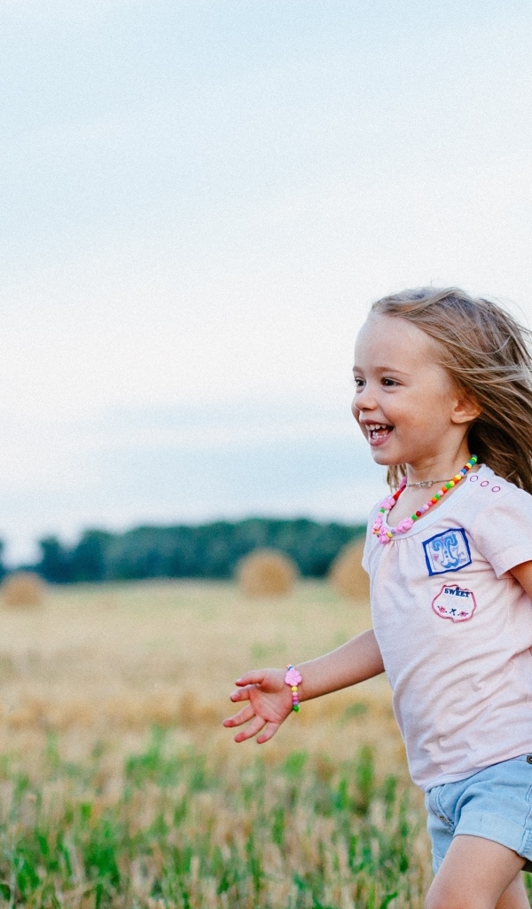 Маленькая веселая девочка бегает по полю