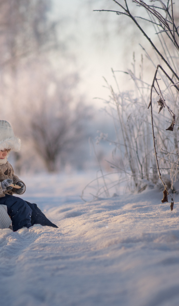 Маленький ребенок на санках в зимнем лесу 