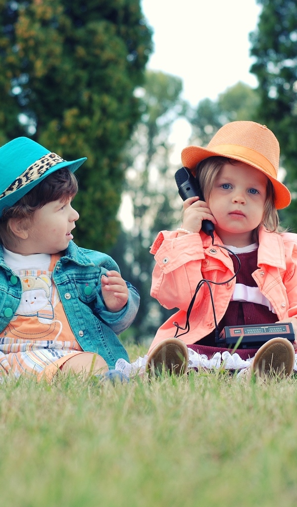 Маленькая девочка и мальчик сидят на траве