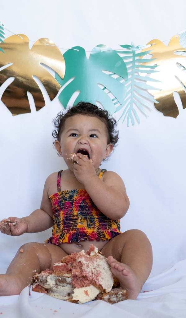 Маленькая девочка ест торт на белом фоне