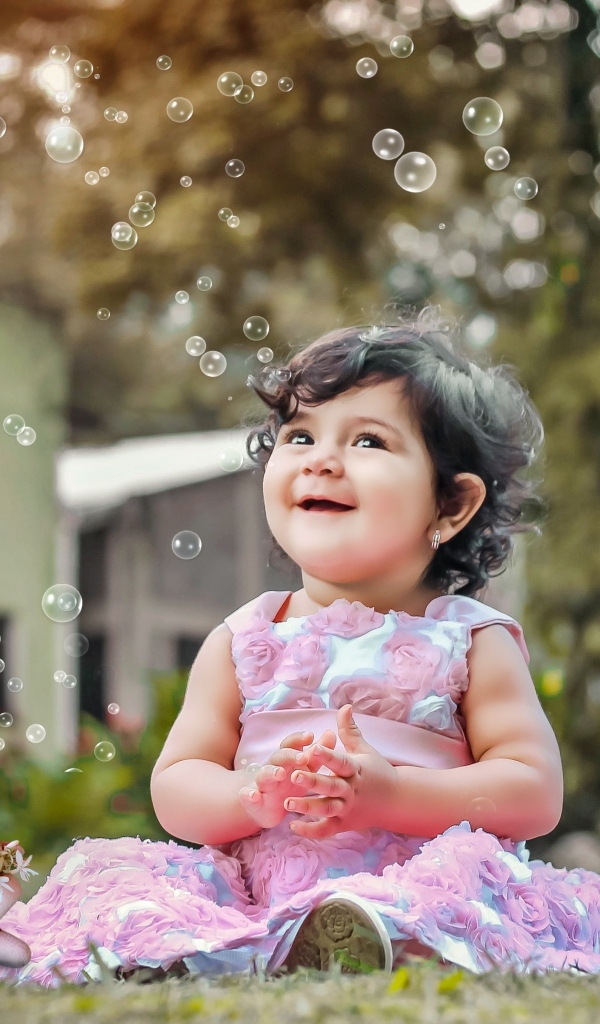 Маленькая девочка радуется мыльным пузырям