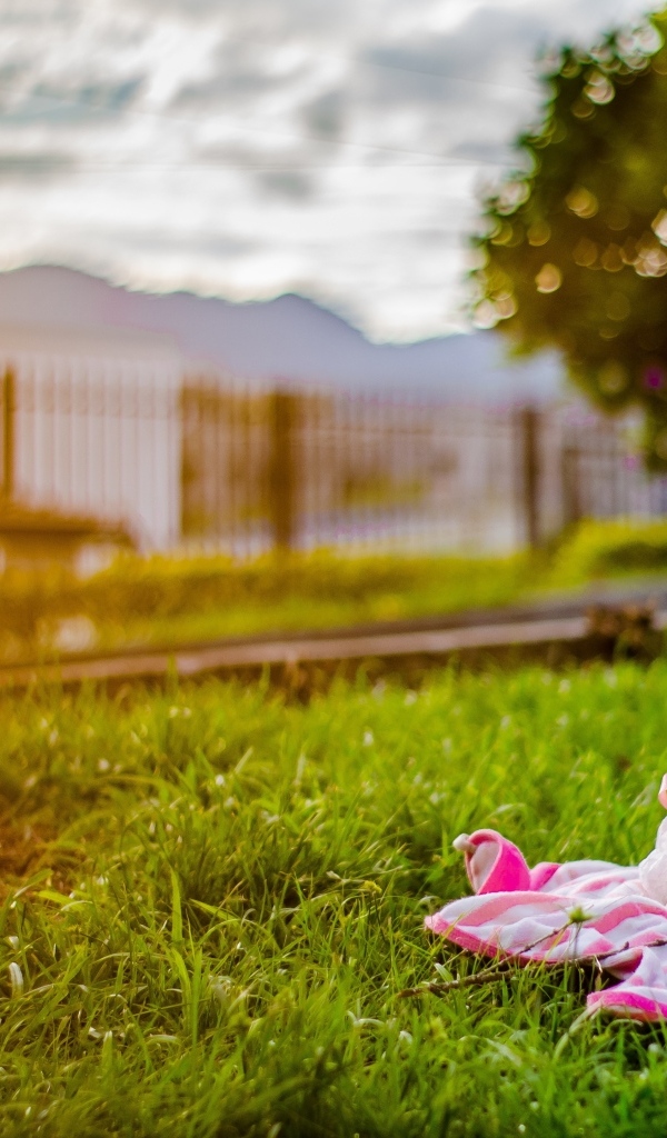 Маленькая девочка в розовом платье сидит на траве