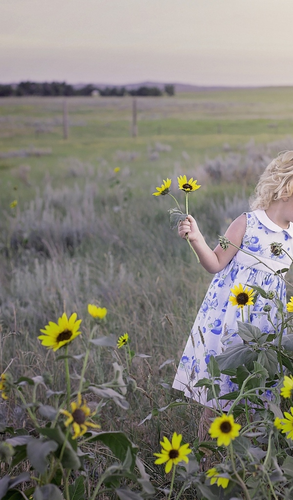 Маленькая девочка собирает желтые цветы