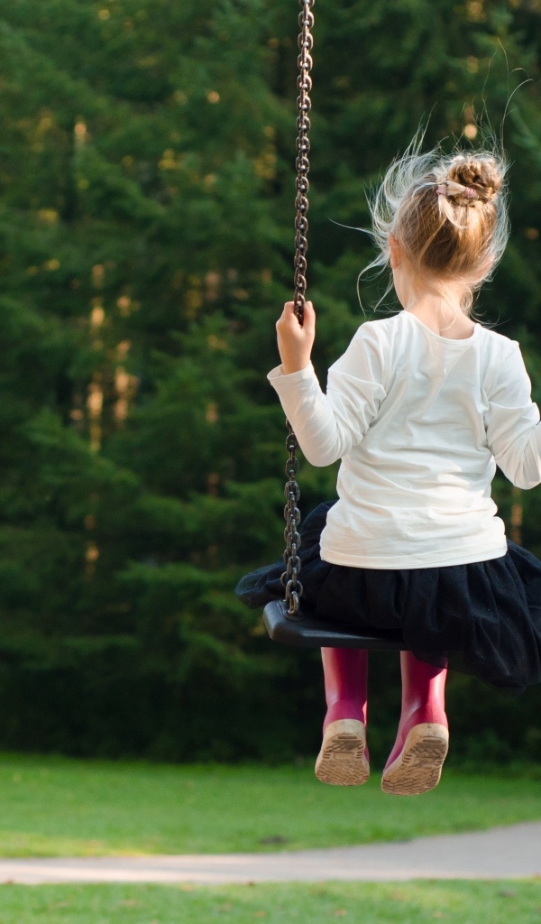 Маленькая девочка катается на качели