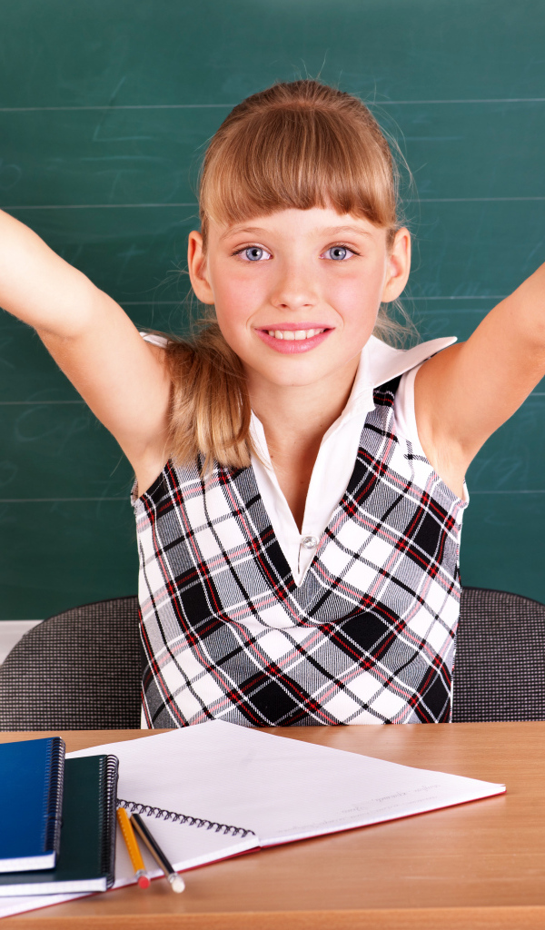 Маленькая девочка школьница в классе за партой 