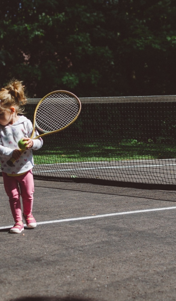Маленькая девочка с ракеткой на поле