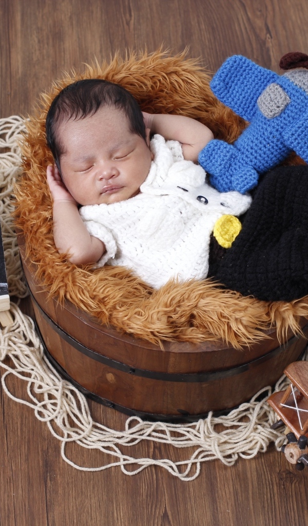 Маленький новорожденный малыш спит в бочке 