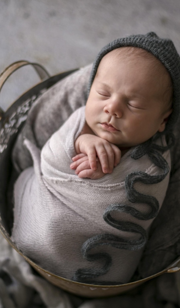 Маленький спящий новорожденный малыш в корзине