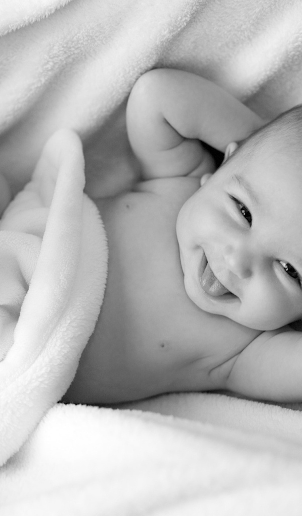 Маленький улыбающийся ребенок в белом покрывале