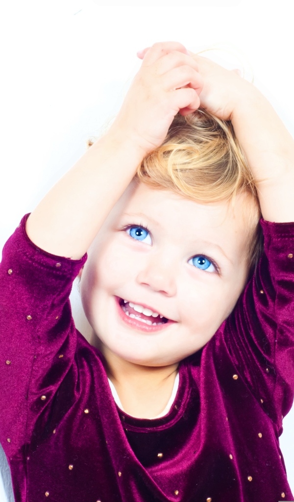 Маленькая улыбающаяся голубоглазая девочка на белом фоне