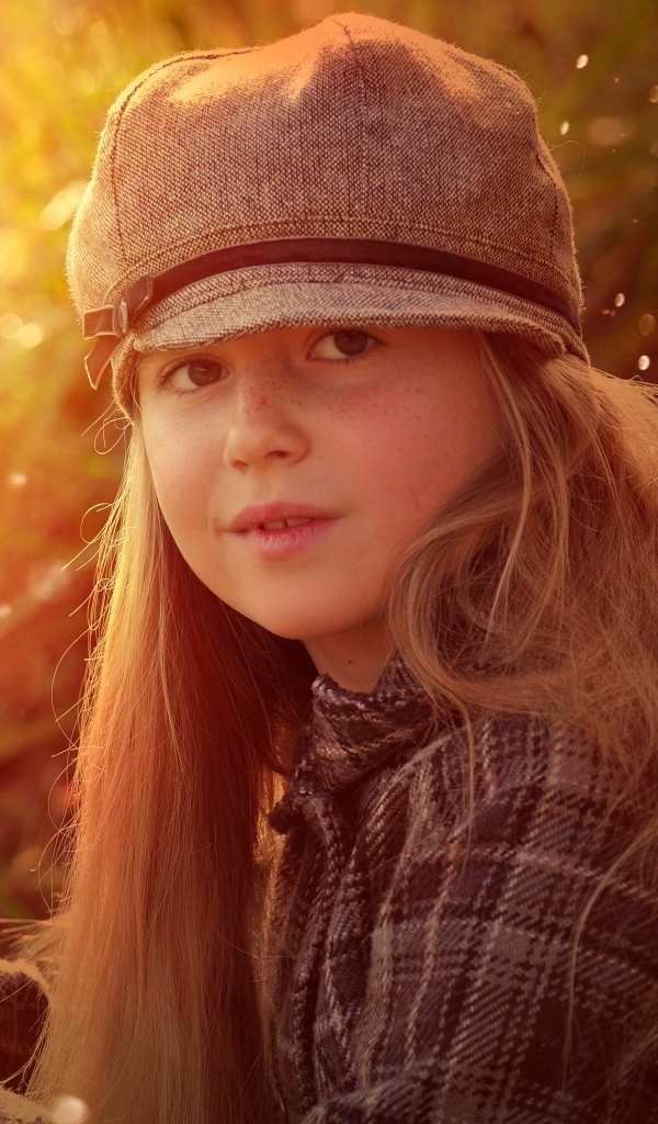 Длинноволосая девочка в кепке в лучах солнца