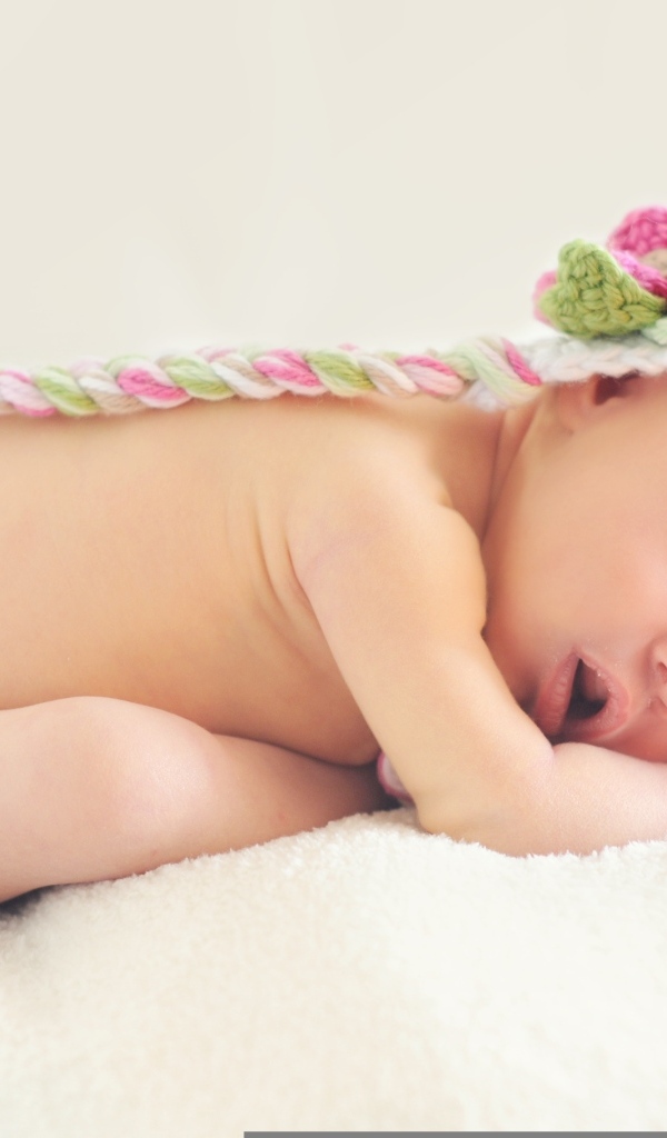 Новорожденная девочка спит в шапке