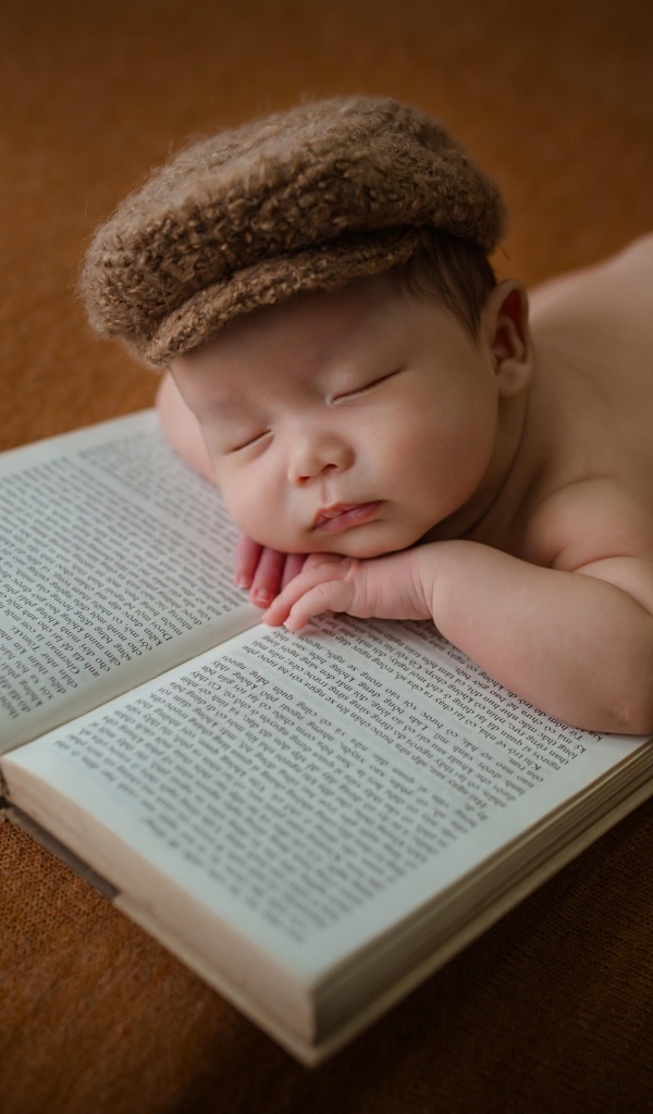 Новорожденный малыш спит на книге