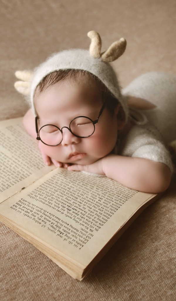Новорожденный ребенок спит с книгой