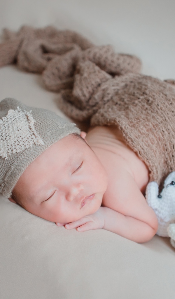 Новорожденный малыш спит на сером покрывале