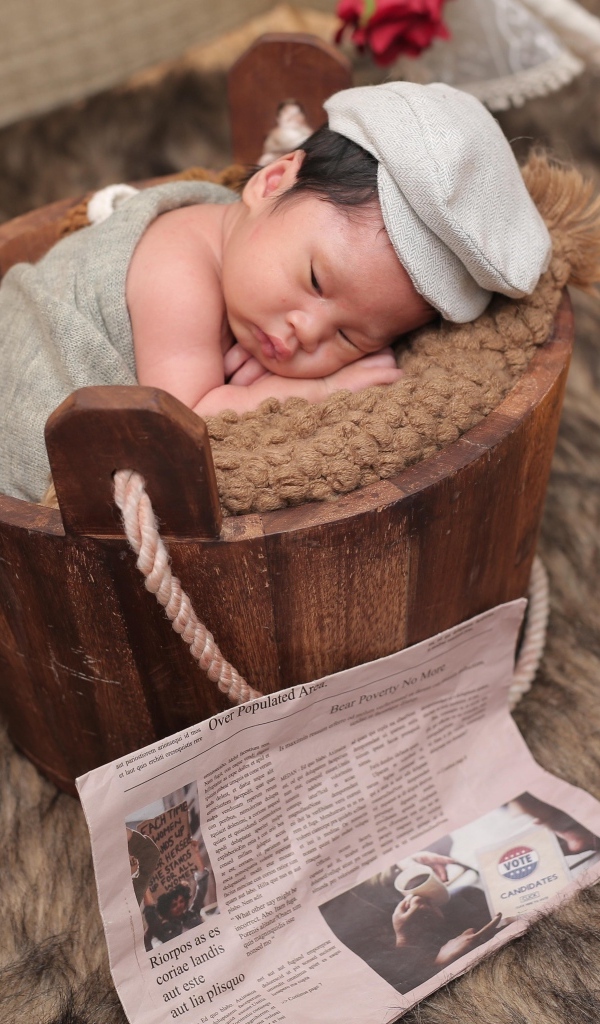 Новорожденный маленький мальчик в деревянном ведре на фотосессии 
