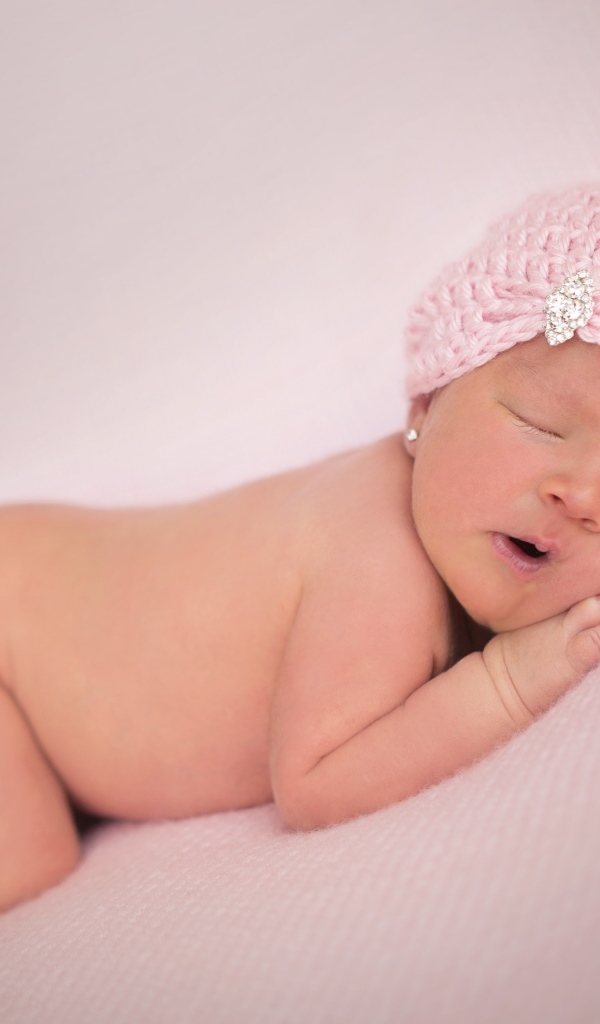 Розовая шапка на голове новорожденной девочки