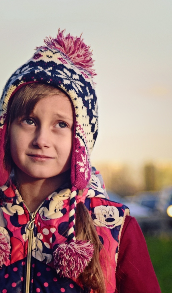 Грустная девочка в теплой шапке на улице