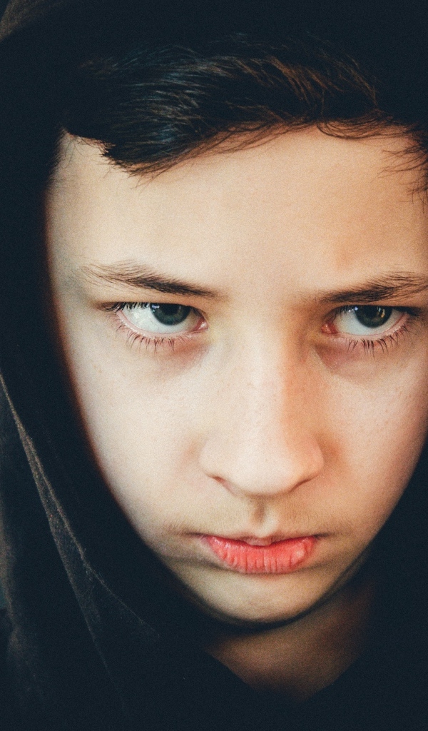 Серьезный мальчик в черном капюшоне