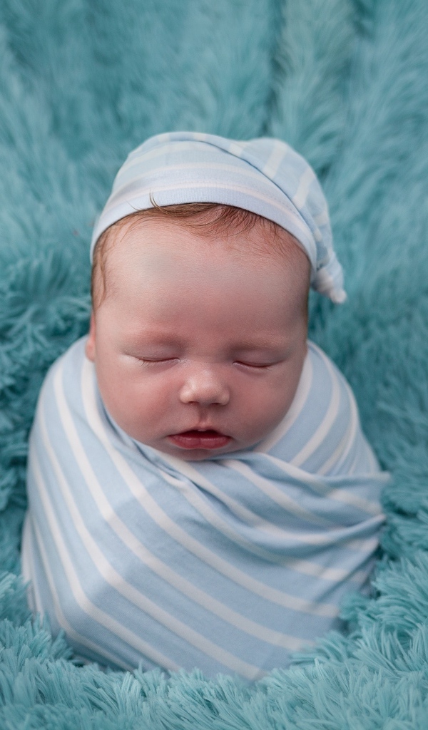Спящий новорожденный малыш на голубом покрывале 