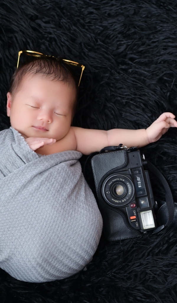 Спящий новорожденный малыш с фотоаппаратом