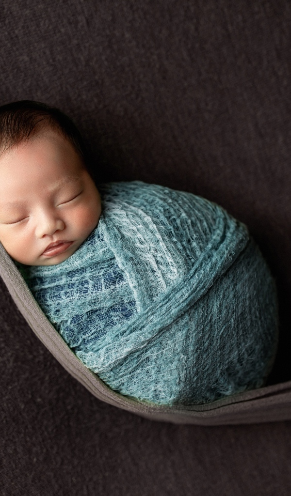 Маленький спящий ребенок завернут в покрывало