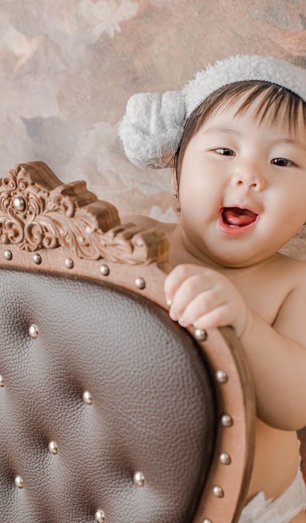 Улыбающийся ребенок азиат стоит у кресла