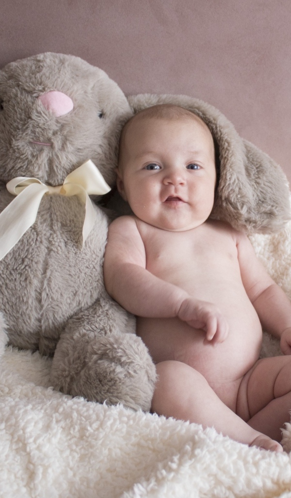 Улыбающийся малыш с игрушечным зайцем