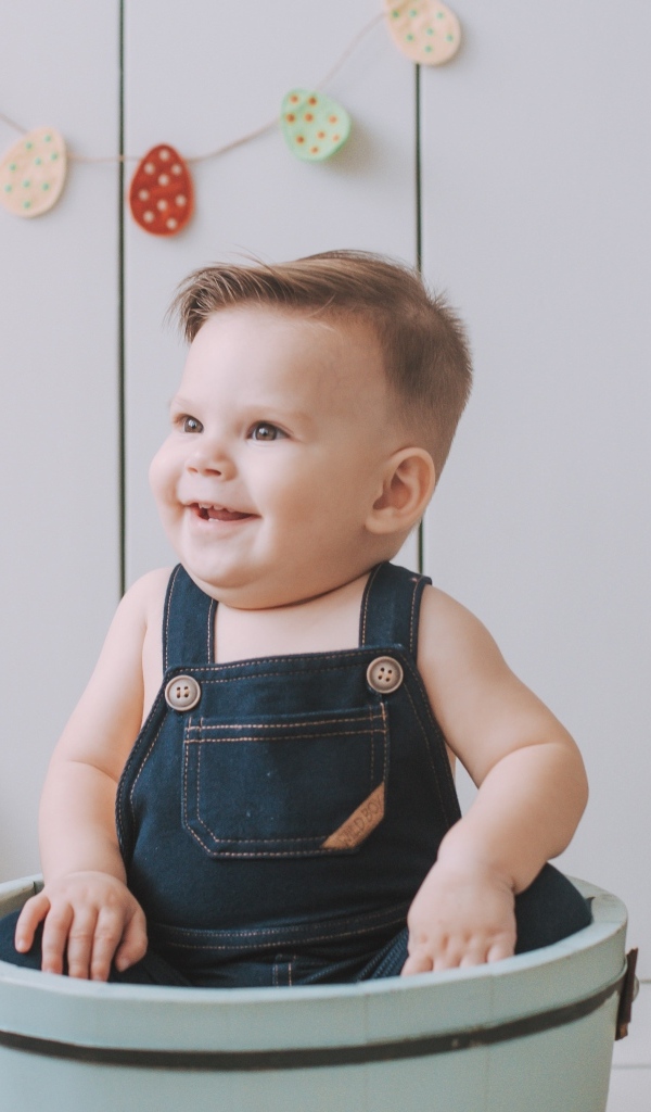 Улыбающийся ребенок сидит в ведре 