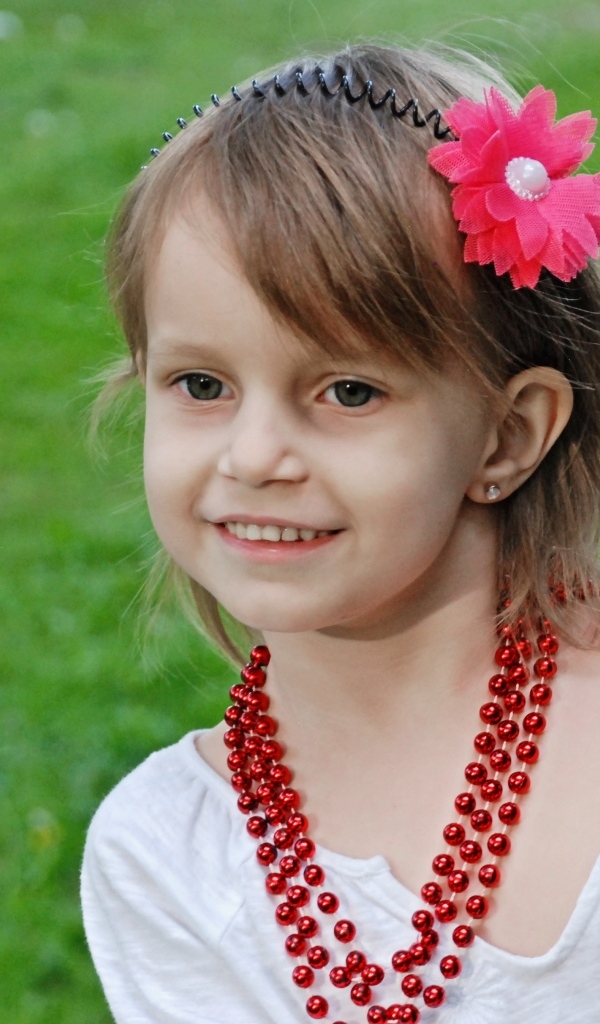 Улыбающаяся девочка стоит у дерева