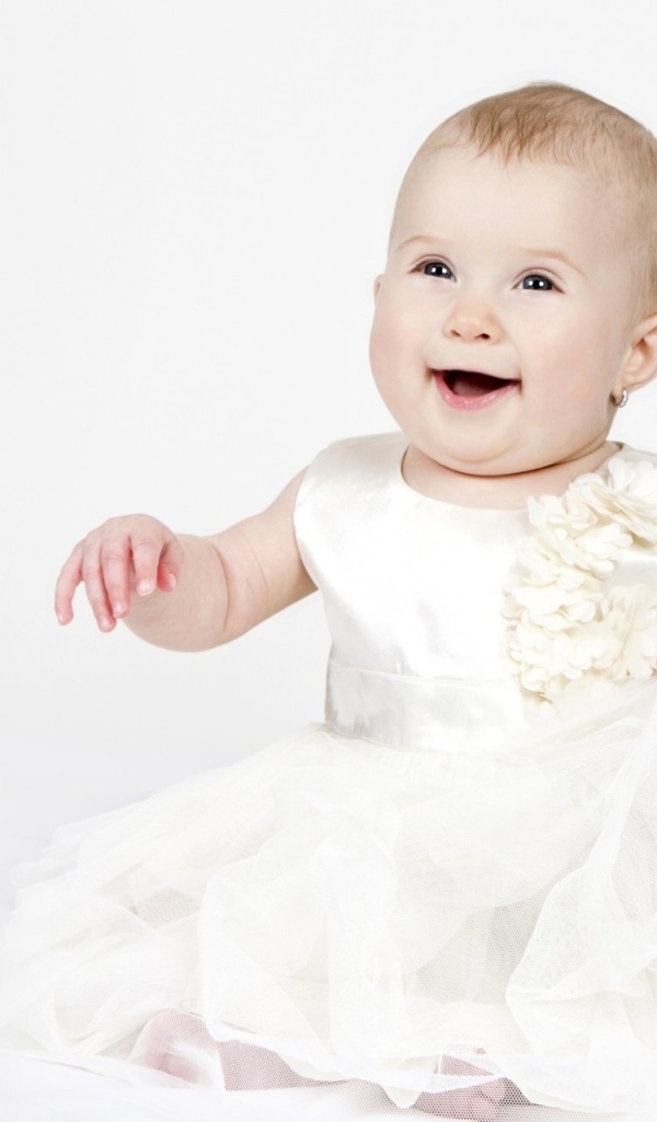 Улыбающаяся маленькая девочка в белом платье 