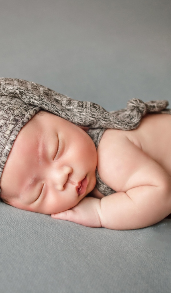 Ребенок спит в костюме на сером покрывале