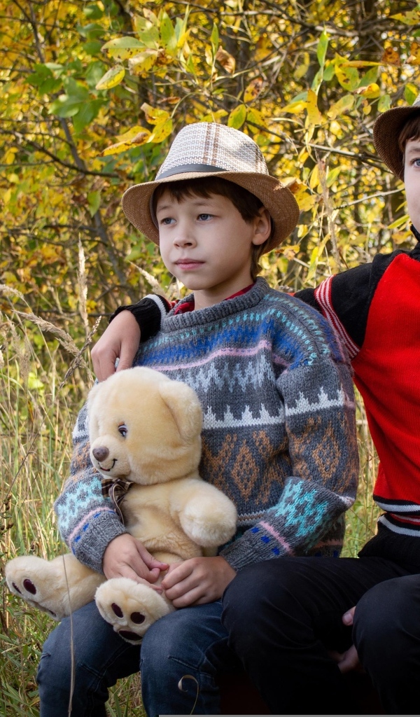 Два мальчика с игрушкой сидят у дерева