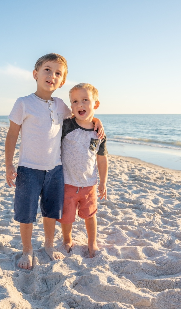Два маленьких мальчика стоят на песке у моря