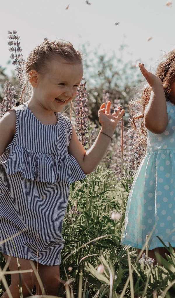 Две маленькие веселые девочки на поле с люпинами