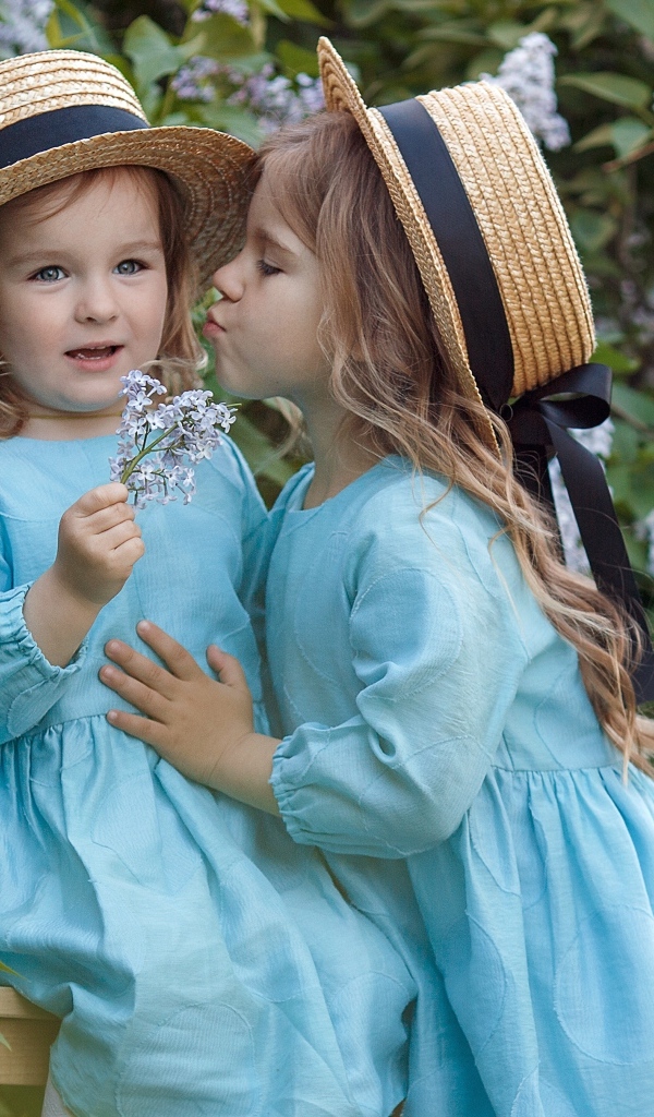 Две маленькие девочки в саду с сиренью