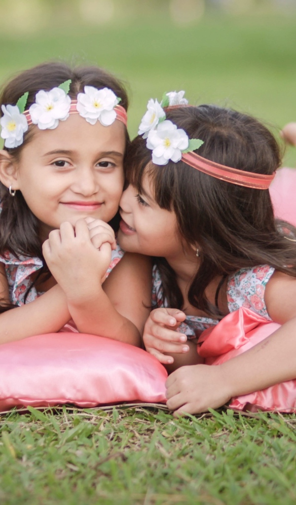 Две маленькие девочки лежат на подушках на траве