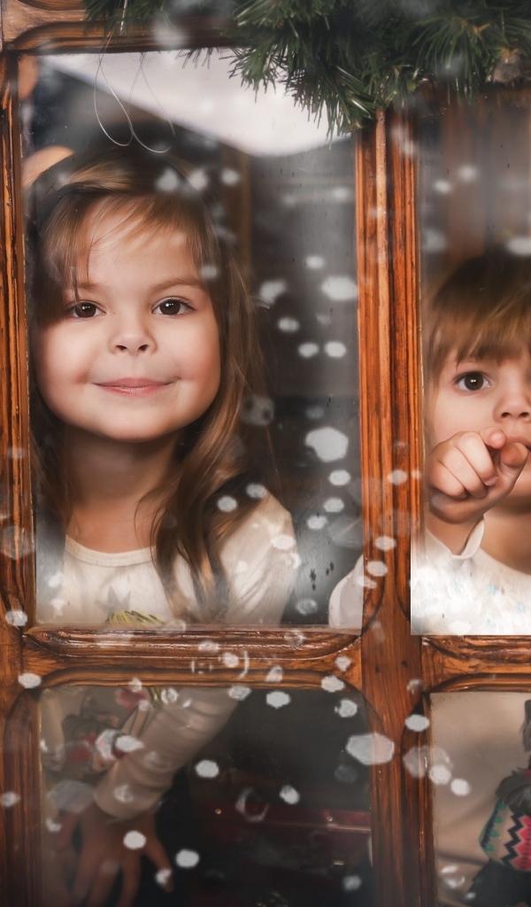 Две маленькие девочки сидят у окна на Рождество