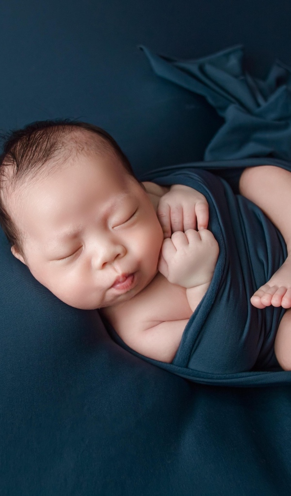 Новорожденный малыш в черном покрывале