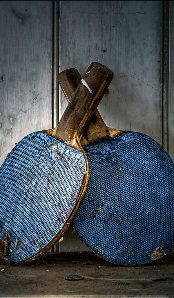 Две старые ракетки для настольного тенниса у стены