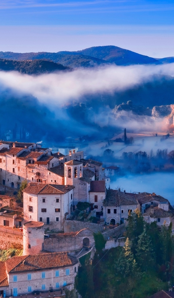 Вид на город на горе в тумане, Италия