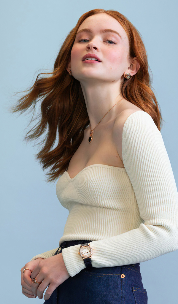 Актриса Сэди Синк в белом свитере на сером фоне