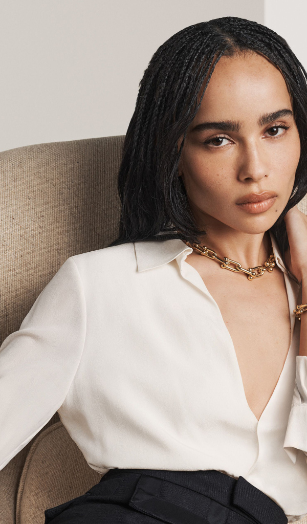 Актриса Зои Кравиц в белой рубашке сидит в кресле