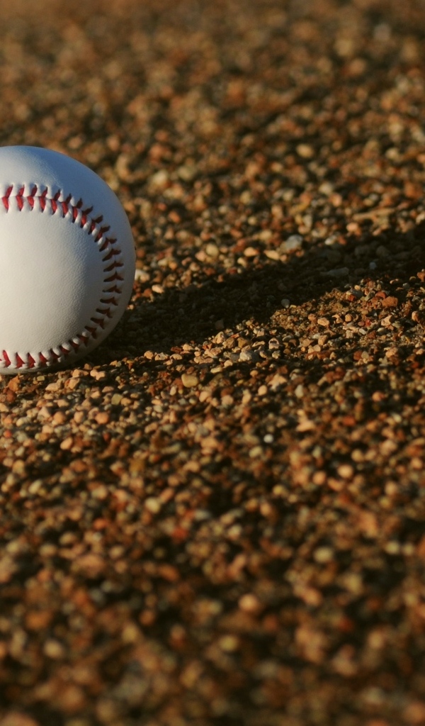 Бейсбольный мяч в лучах солнца на асфальте