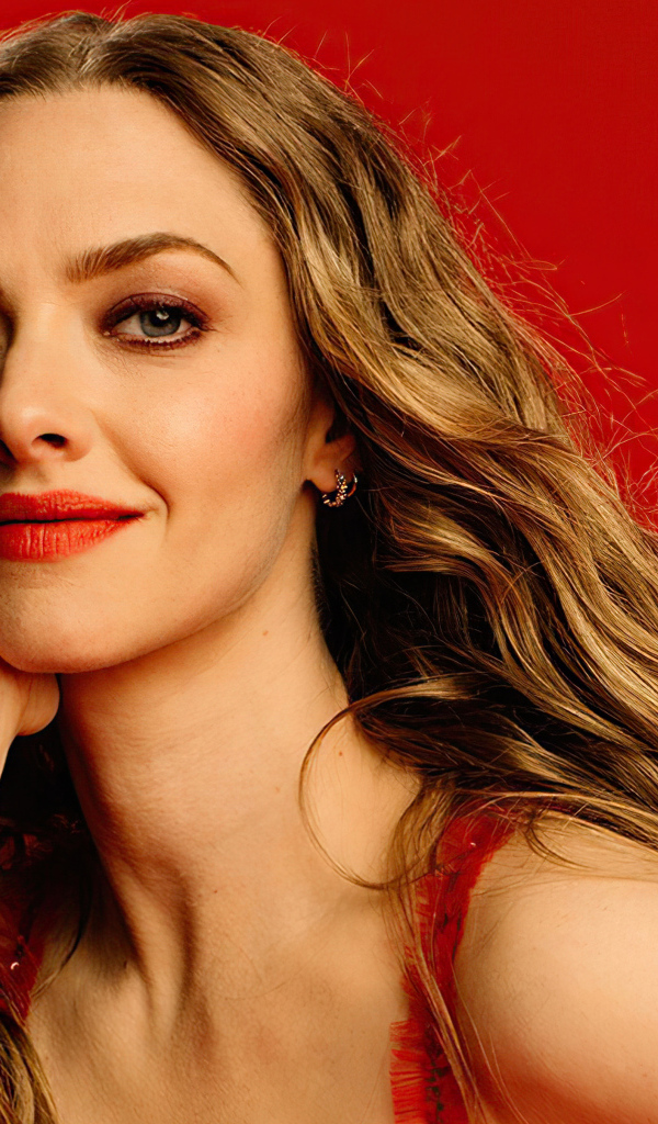 Красивая блондинка Аманда Сайфред на красном фоне